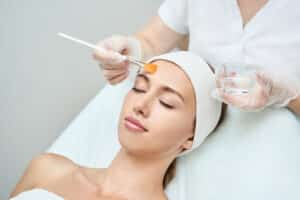 Woman happily having a chemical peel applied to her face for smoother, brighter skin