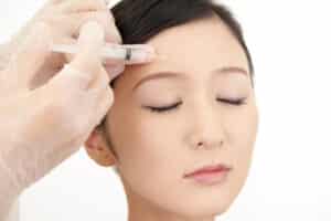 Young woman getting Botox injections to her forehead to prevent future wrinkles from forming