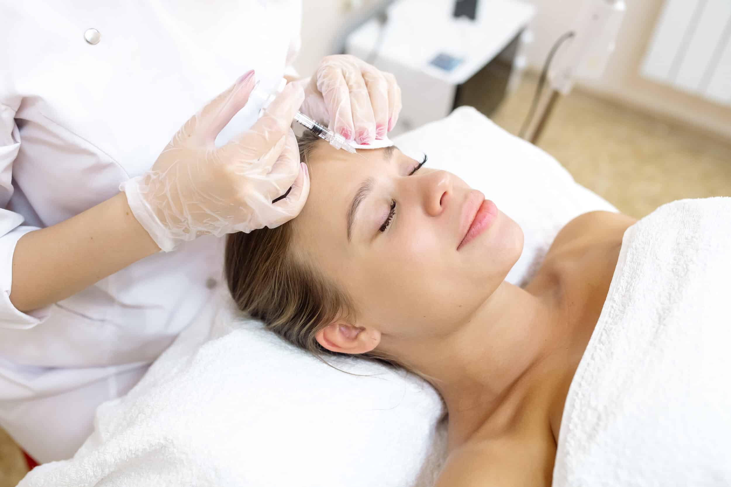 Young woman in a spa-like setting getting Xeomin injections to smooth lines between her eyebrows
