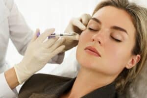 Close up of a beautiful woman receiving dermal filler injections to her cheeks to maintain a youthful, sculpted look