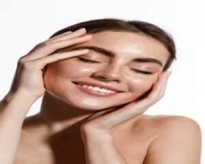 Woman touching her face and smiling after getting a DiamondGlow facial for bright, energized skin