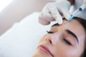 Close-up of a happy young woman receiving Xeomin injections between her brows for subtle enhancement.